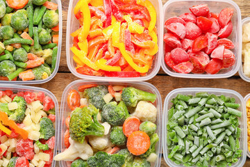 Plastic containers with frozen vegetables on wooden background, closeup