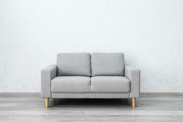 Stylish cozy sofa near light wall