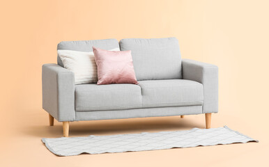 Stylish cozy sofa on color background