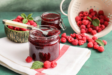 Jars with sweet raspberry jam on table