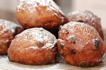 Dutch deep-fried raisins buns with powdered sugar and raisins on a wooden plate