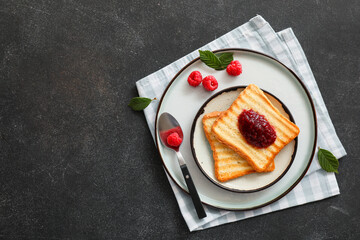 Toasts with sweet raspberry jam on dark table