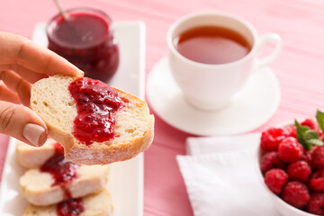 Female hand and bread with sweet raspberry jam on table, closeup