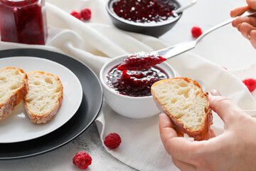Woman spreading sweet raspberry jam on bread, closeup