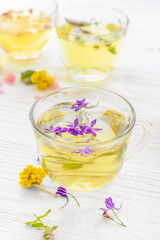 Cups with floral tea on light background