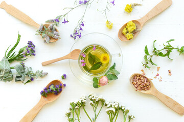 Flowers, spoons and cup with floral tea on light background