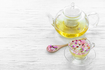 Teapot and cup with floral tea on light background