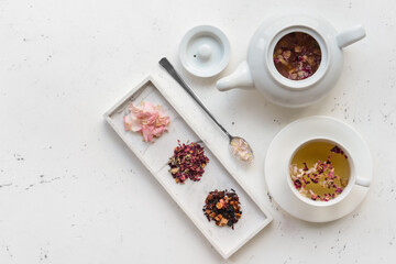 Dry flowers, teapot and cup with floral tea on light background