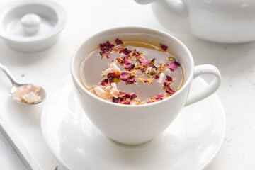 Cup with floral tea on light background