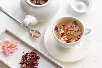 Dry flowers, teapot and cup with floral tea on light background