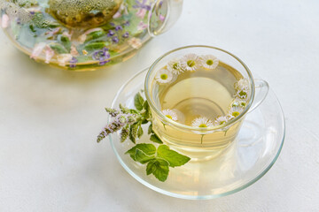 Cup with herbal tea on light background