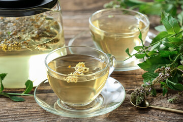 Teapot and cups with herbal tea on wooden background