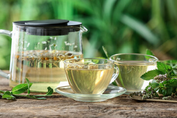 Teapot and cup with floral tea on table against blurred background