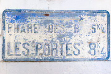 Old french road sign directive on a wall, ancient metal plate, Ars en Re, Ile de Re, Charente...