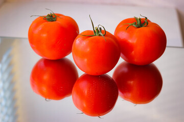 Several red tomatoes on a mirror surface
