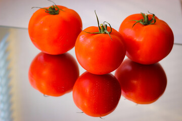Several red tomatoes on a mirror surface