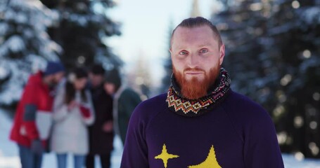 Attracive young man with ginger hair and beard looking into camera wearing cozy xmas sweater. Caucasian people. Male portraits. Winter landscape.