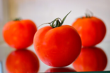 Several red tomatoes on a mirror surface