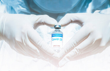 COVID-19 coronavirus vaccine with a vial in the hand wearing medical latex gloves form a heart...