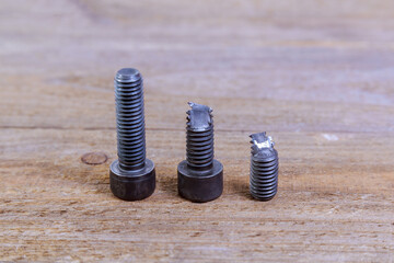 Broken black bolt isolated on wooden background.