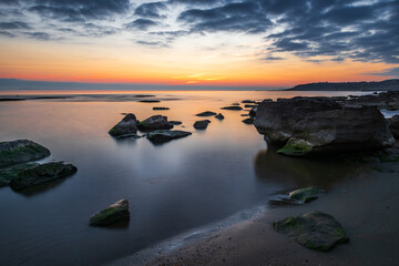 Fototapeta na wymiar Colorful sunrise on the rocky sea coast, long exposure