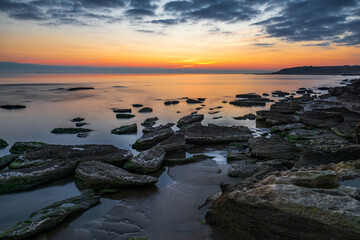 Colorful sunrise on the rocky sea coast, long exposure
