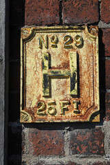 Close Up of Old 19th Century Cast Metal Plaque on Painted Wall 