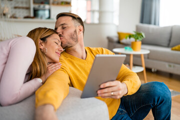 Happy couple spending time with tablet at home