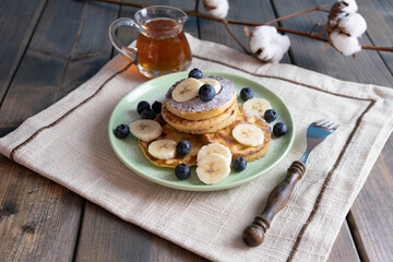 morning breakfast with tea, pancakes with berries and bananas on a plate