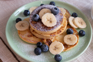 fresh pancakes with berries and sliced bananas on a plate, morning breakfast