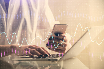 Double exposure of financial graph sketch hologram and woman holding and using a mobile device. Stock exchange concept.