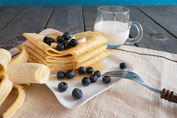 blueberries, freshly baked pancakes poured with honey and fresh bananas in the plate