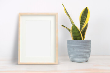 Home interior poster mock up. Wooden frame next a plant in a grey ceramic pot. Empty copy space for Editor's text.