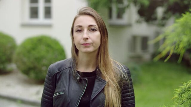 Face of a blonde girl in the garden who is turning her head left.
