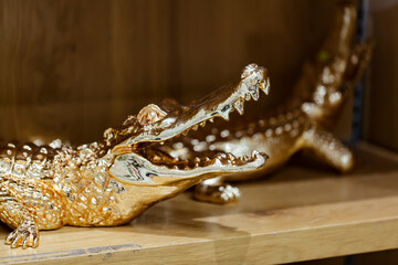 Crocodile golden sculpture on on wooden table. Alligator statue with open mouth. Beautiful jewelry...