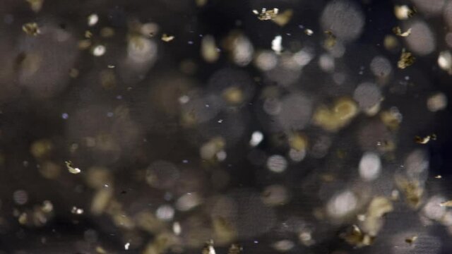 Gold leaf floating in gin Christmas liquor drink macro detail