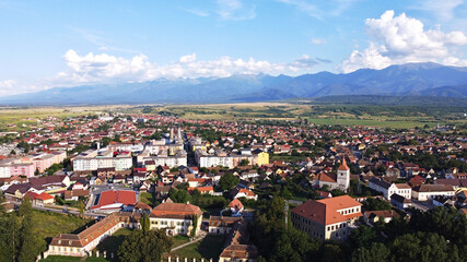 Fototapeta premium Drone panoramic view of small town in Transylvania, with the Carpathian mountains in the back