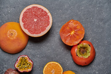 Close up of orange, grapefruit, and kaki on dark background, top view.