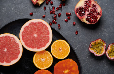 Close up of a plate full of vitamin C fruits on a dark background.