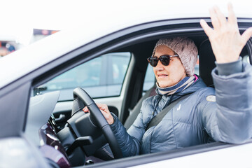 Elderly person with glasses driving and showing anger at slow traffic. traffic jam in the city.