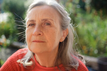 Portrait of a mature woman with grey hair spending time outdoors during sunny day, happy retirement