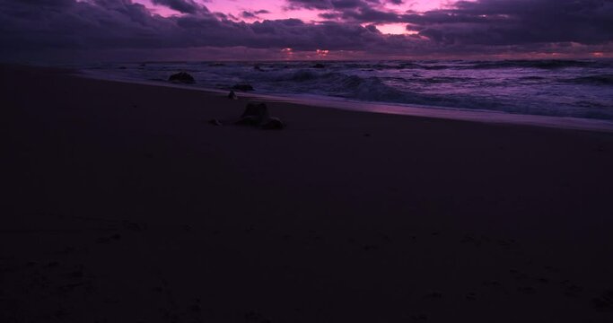 Dark beach at dusk in winter with vivid purple sky. Pan up from sand to sky.