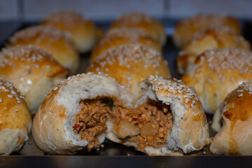 A tray of chicken filled meat buns with sesame seeds