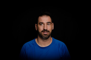 Fototapeta premium Bearded man dressed in blue t-shirt posing against black background