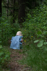 Young girl sitting on a path in a blue dress