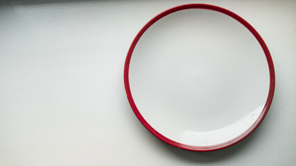 Empty white plate with red border on white background.