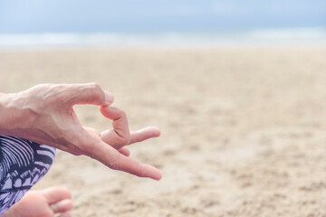 close up yoga hand meditating on the beach