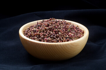 Sichuan pepper (zanthoxylum bungeanum) in a wooden bowl. Chinese prickly ash.