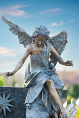 schöner Engel sitzt auf einem Grabstein © Blende8