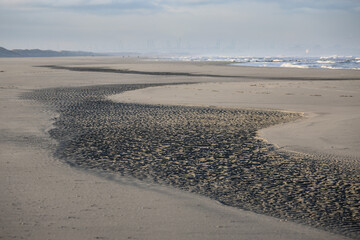 Beach face with winding light and dark sand looking towards the North Sea